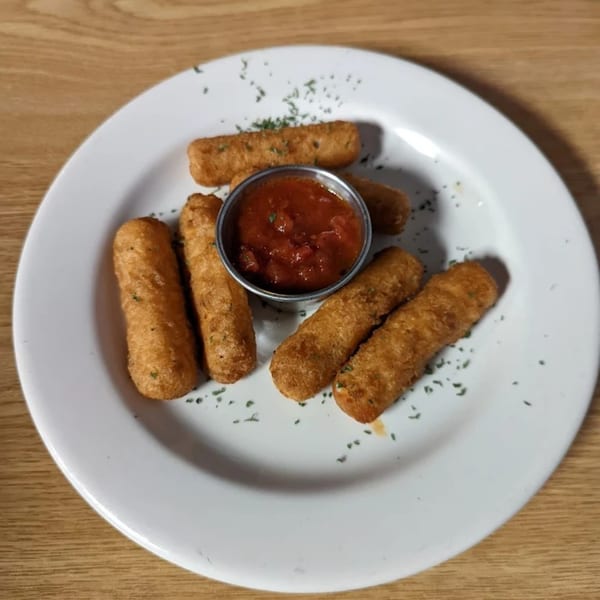 Golden-brown mozzarella sticks with a side of marinara sauce on a white plate at Mama Mia's.