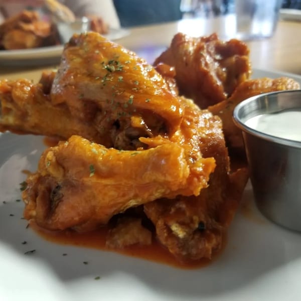 A plate of Mama Mia's Italian Restaurant's buffalo wings with a side of ranch dressing.